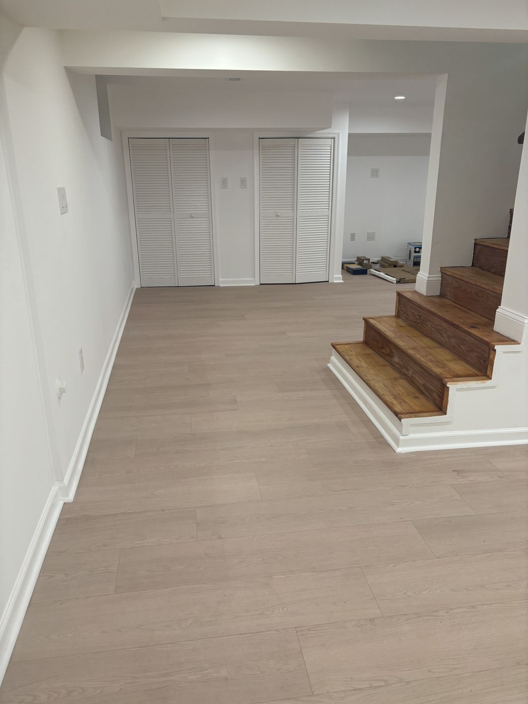 Finished basement by TNK with light luxury vinyl plank flooring, white trim, closets and wood stairs