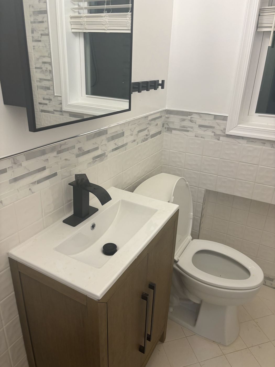 Bathroom remodel by TNK with wood vanity, matte black faucet and marble mosaic tile accent